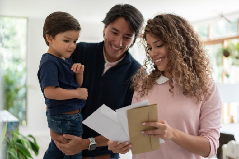 Young family smiles while looking through mail. iZ4eHME