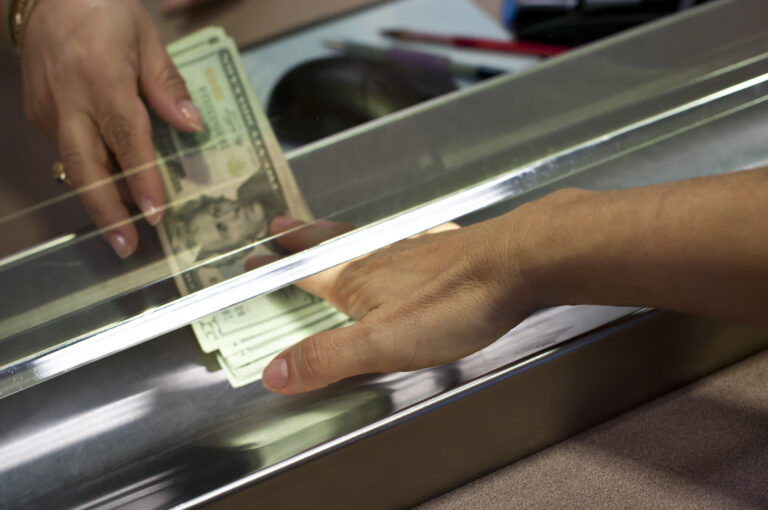 american currency being exchanged across a bank teller window