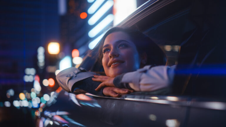 happy person leaning out of a car window while riding at night