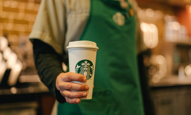 starbucks employee holding cup with logo sbux