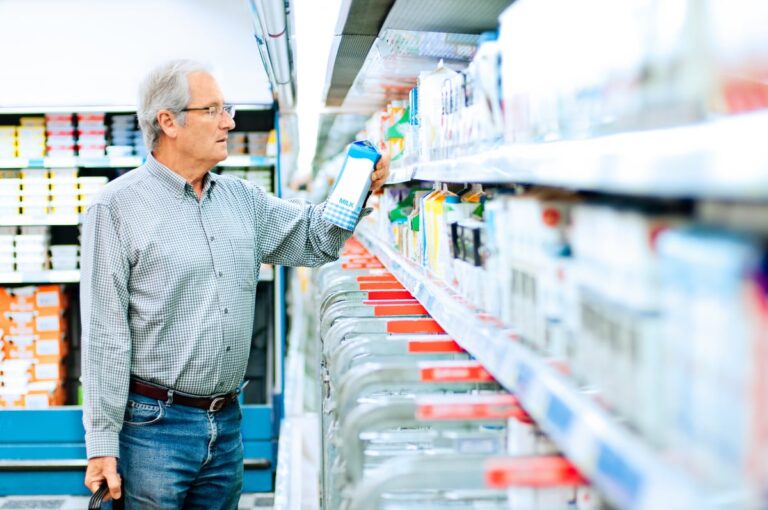 Mature man reads the label on a milk carton ipaXdLc