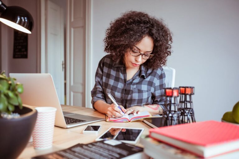 Woman taking notes while using a laptop IpOrUzu