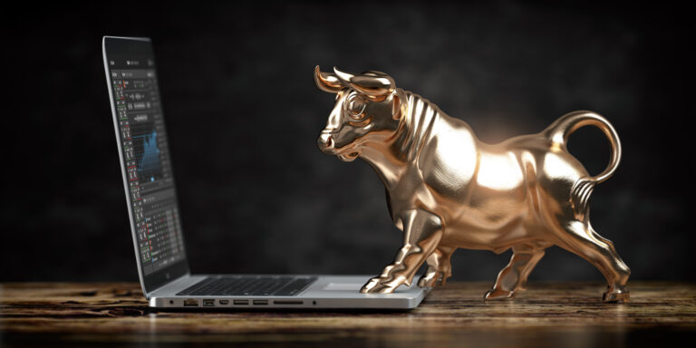 a sculpture of a golden bull standing on a laptop computer