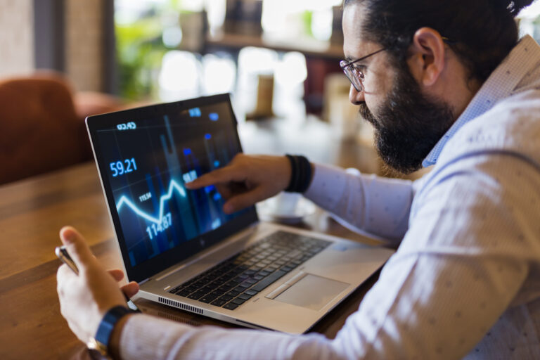 man in specs looking at a line chart on a laptop