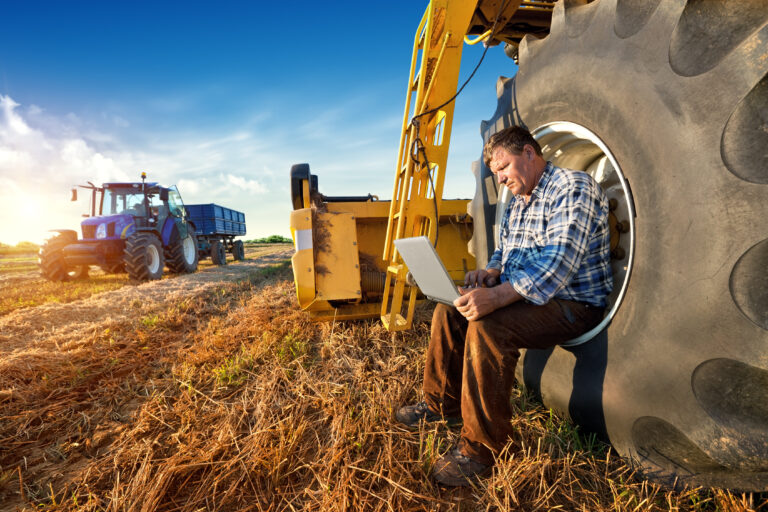 man sits in the wheel of a tractor while looking at a computer