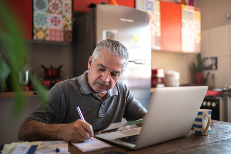 senior man laptop taking notes gettyimages 1278336166