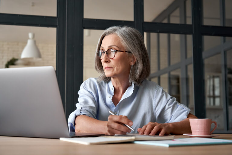 a person at a laptop holding a pen gettyimages 1281173451