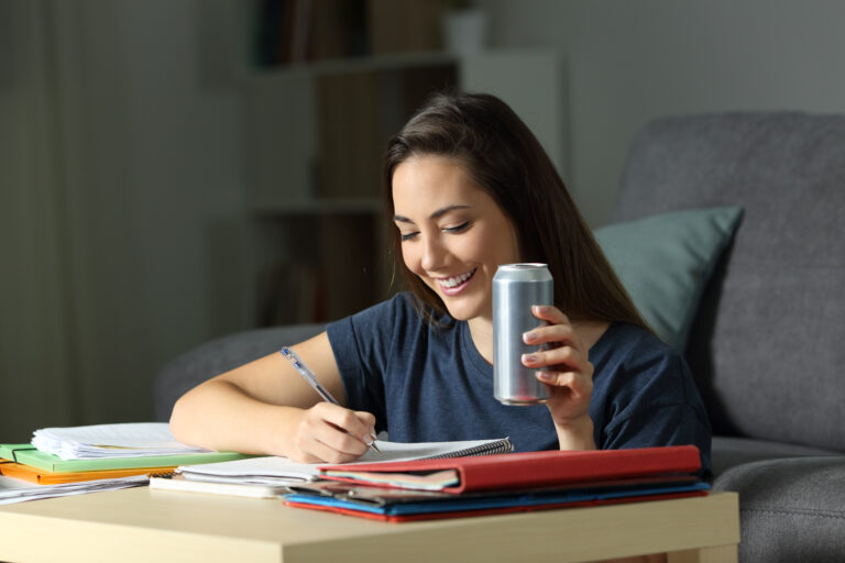 lady studies in a home setting holding a beverage can