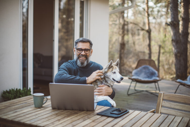 older man at laptop with dog gettyimages 1214136074