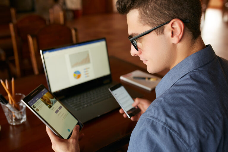 person wearing glasses looking at multiple electronic devices