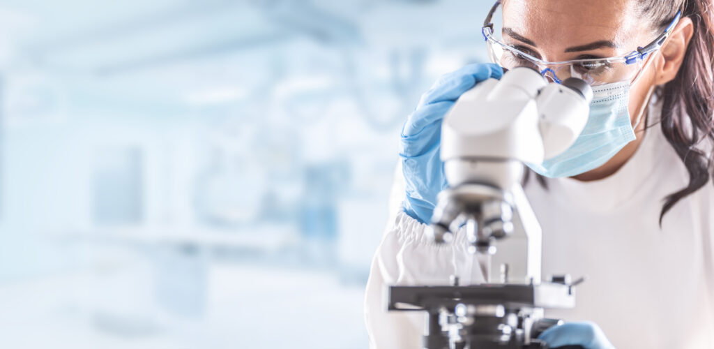 person in a lab gazing into a microscope