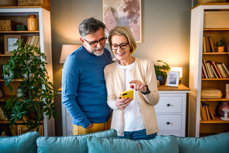 2 elderly people looking at a phone with stocks