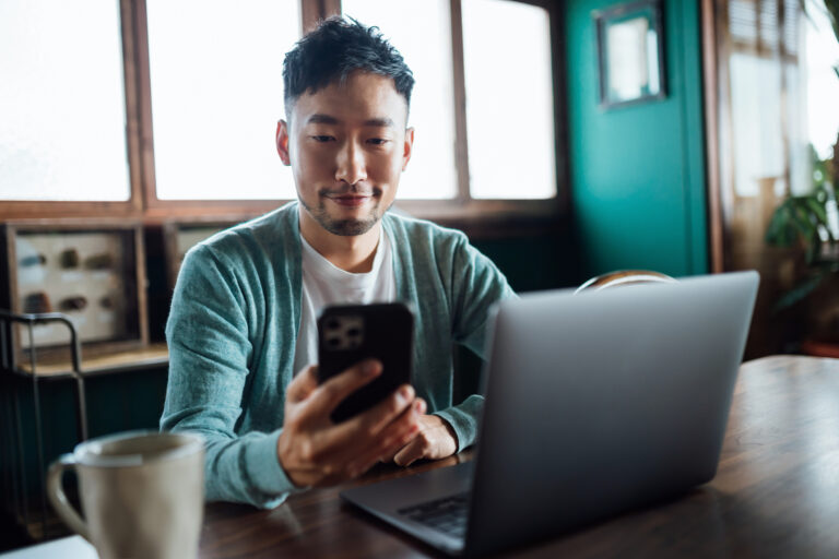 investor looks at phone laptop
